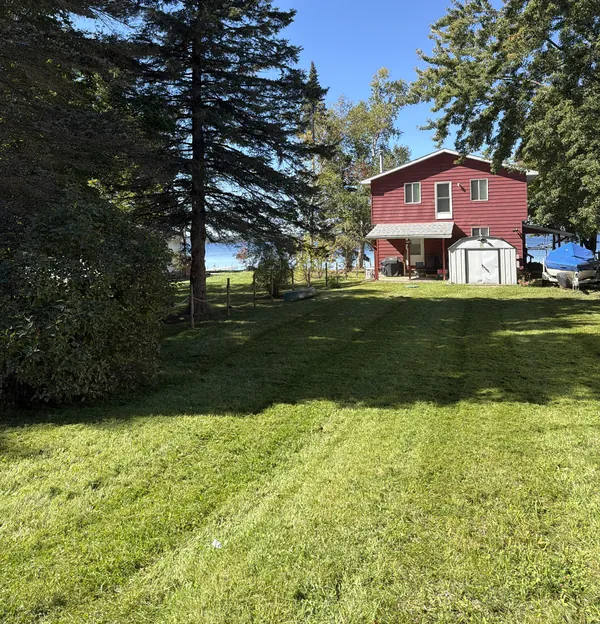 Striped lawn running down to a red lakeside house