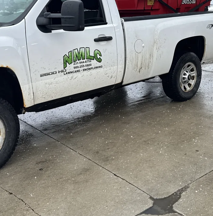 White NMLC lawn care and snowplowing pickup with a red BOSS salt spreader